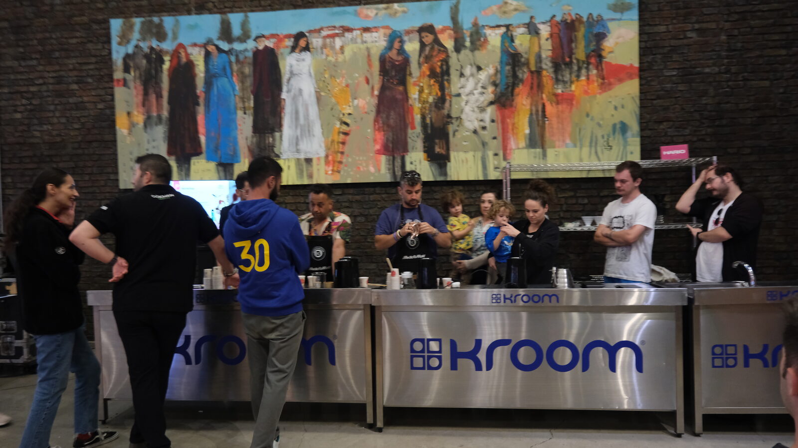 Staff serving along a long bar counter in front of a painted mural
